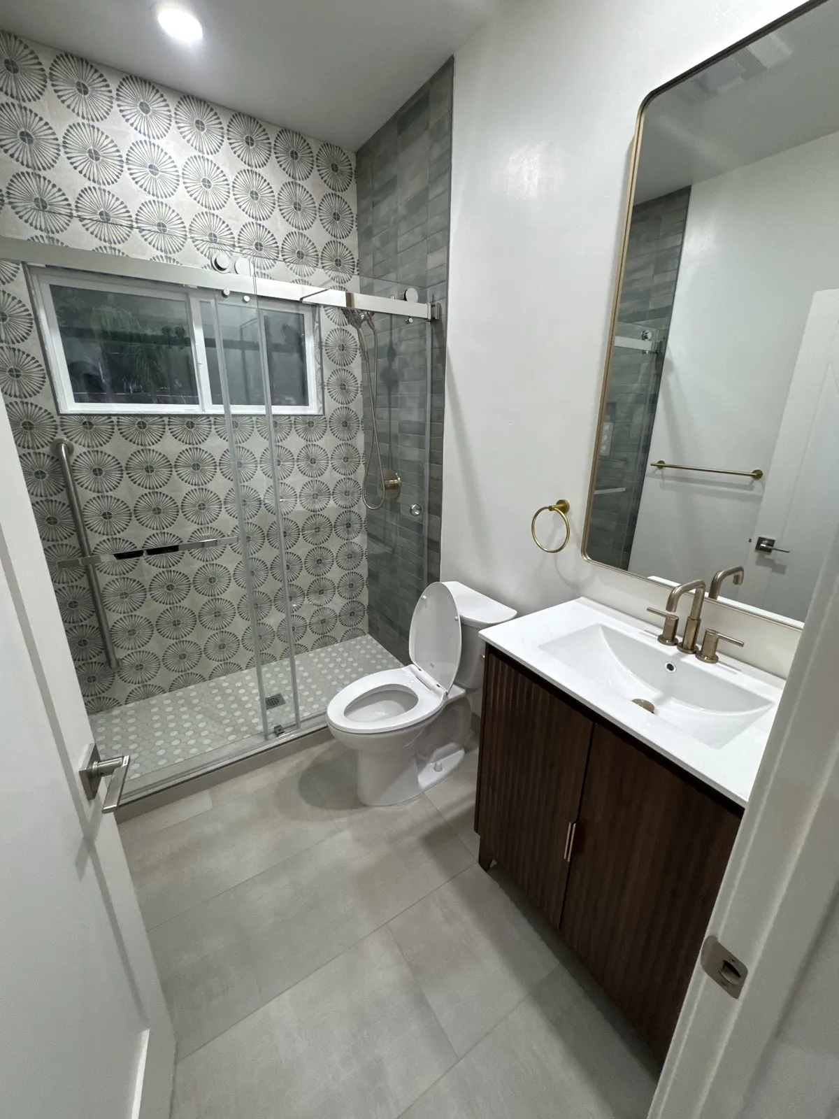 Bathroom with patterned tile shower and walnut vanity