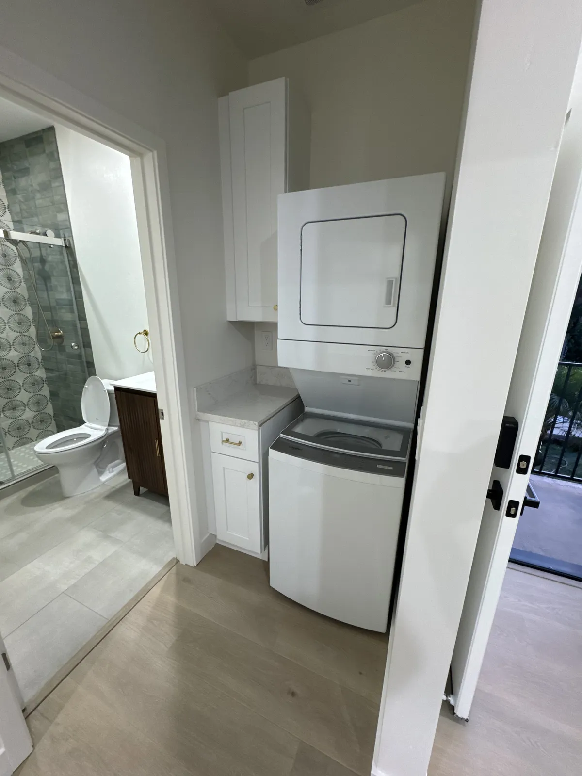 Bathroom with stacked laundry and tiled shower