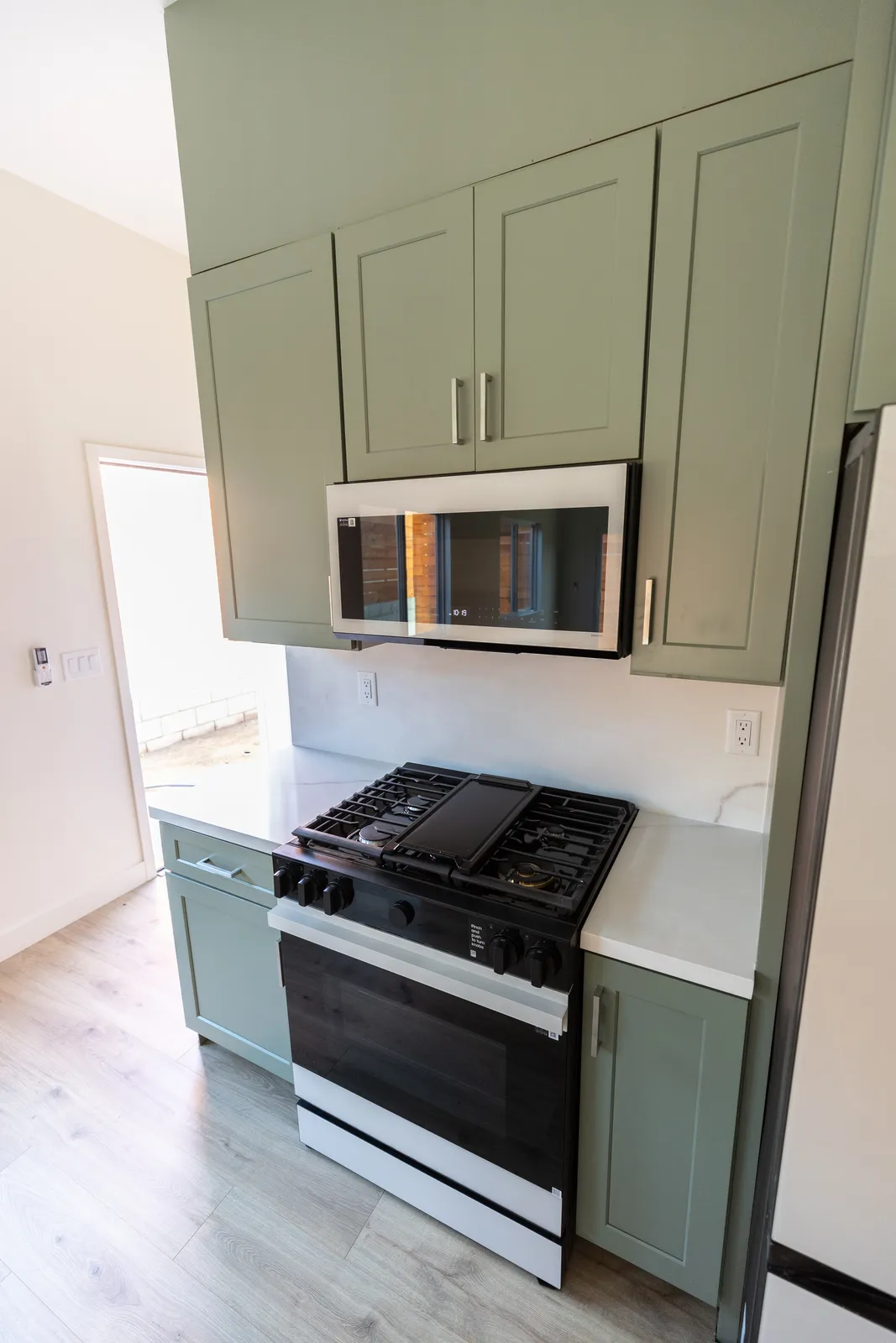 Kitchenette with sage cabinetry and stainless range
